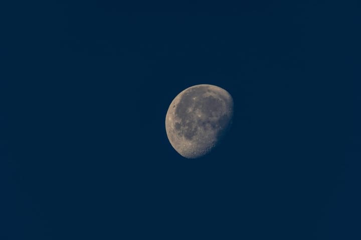 grey waning gibbous moon in a deep blue sky