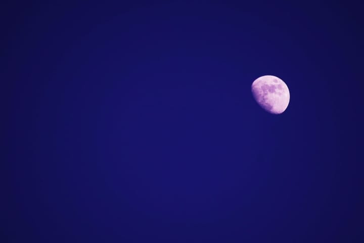 lilac-shadowed waxing gibbous moon in a deep violet sky