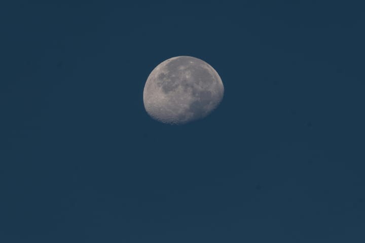 grey waning gibbous moon on a grey-blue sky